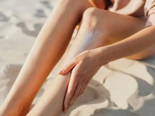 Femme s'appliquant une crème solaire sur les jambes