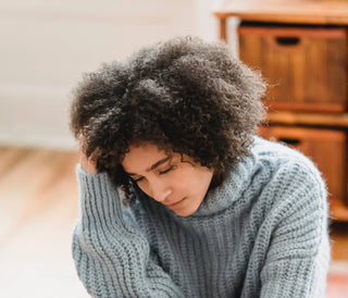 femme assise se grattant le cuir chevelu
