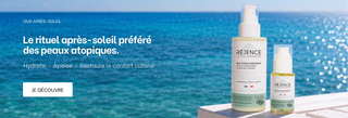 Le gel-crème hydratant et le sérum-huile apaisant posés sur une rambarde avec la mer en arrière plan.