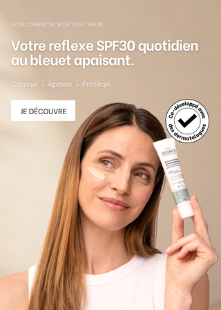 Femme tenant le soin correcteur de teint SPF30 dans ses mains avec la texture du soin sur sa joue 