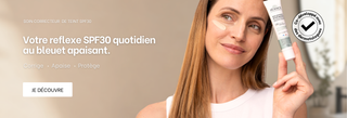 Femme tenant le soin correcteur de teint SPF30 dans ses mains avec la texture du soin sur sa joue 