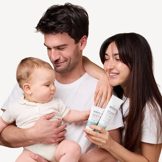 Famille avec un bébé tenant plusieurs soins de la Routine Complète Eczéma Réjence, illustrant une routine adaptée aux nourrissons, enfants et adultes ayant une peau sensible ou à tendance atopique.