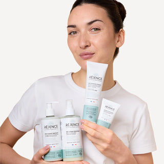 Femme présentant les quatre soins de la Routine SOS Eczéma Atopique Réjence : Soin Lavant Apaisant, Gel-Crème Hydratant, Crème riche SOS sécheresses et squames et Cold cream SOS rougeurs et démangeaisons.